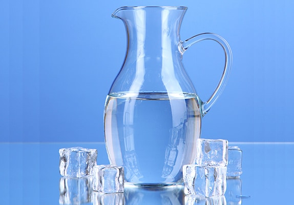 Une carafe et des glaçons, le tout sur fond bleu